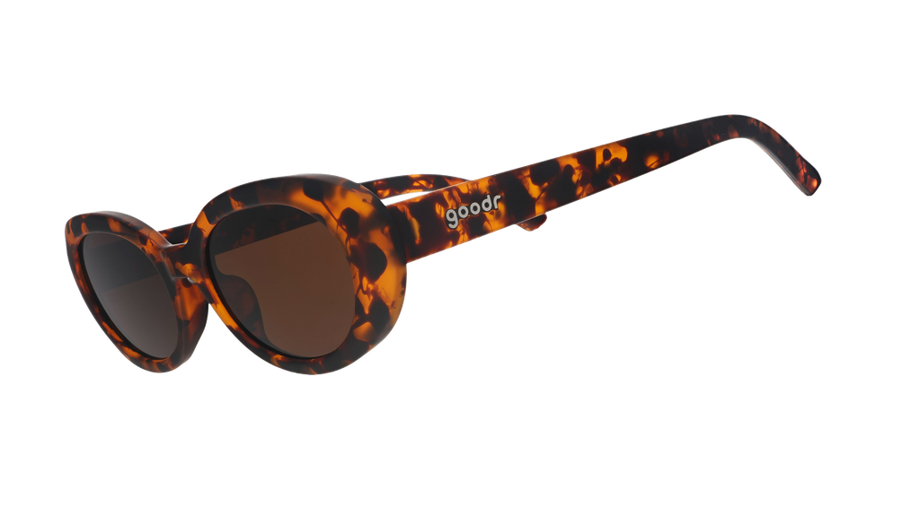 Three-quarter angle view of oval tortoiseshell sunglasses with brown polarized lenses against a white background.