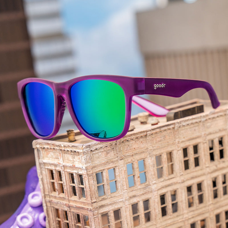 A pair of purple sunglasses withe reflective green and blue lenses.