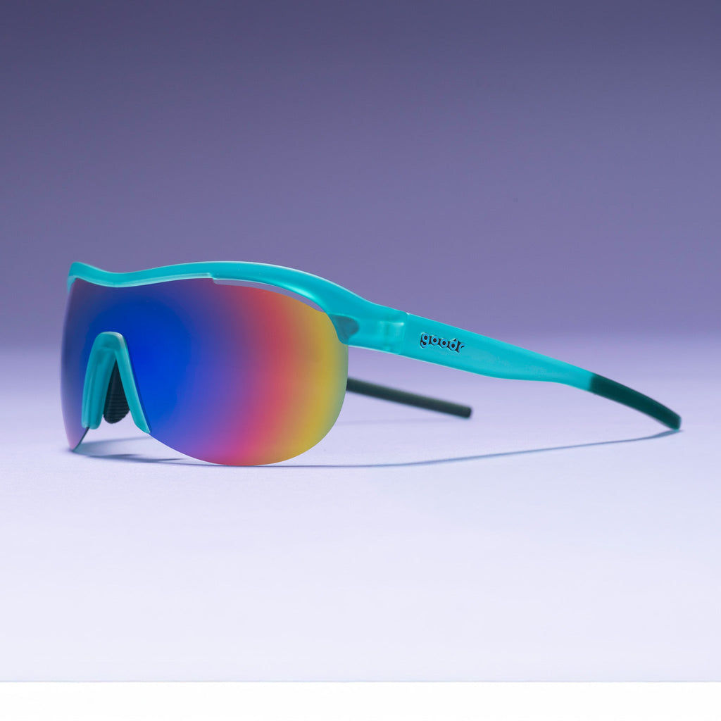 Left three-quarter angle view of translucent mint green wrap shield sunglasses with white-blue reflective lenses on a tabletop.