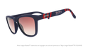 Three-quarter angle view of shades tilted down. Blue + red frames w/ Bold City on temples. Brown gradient lenses.