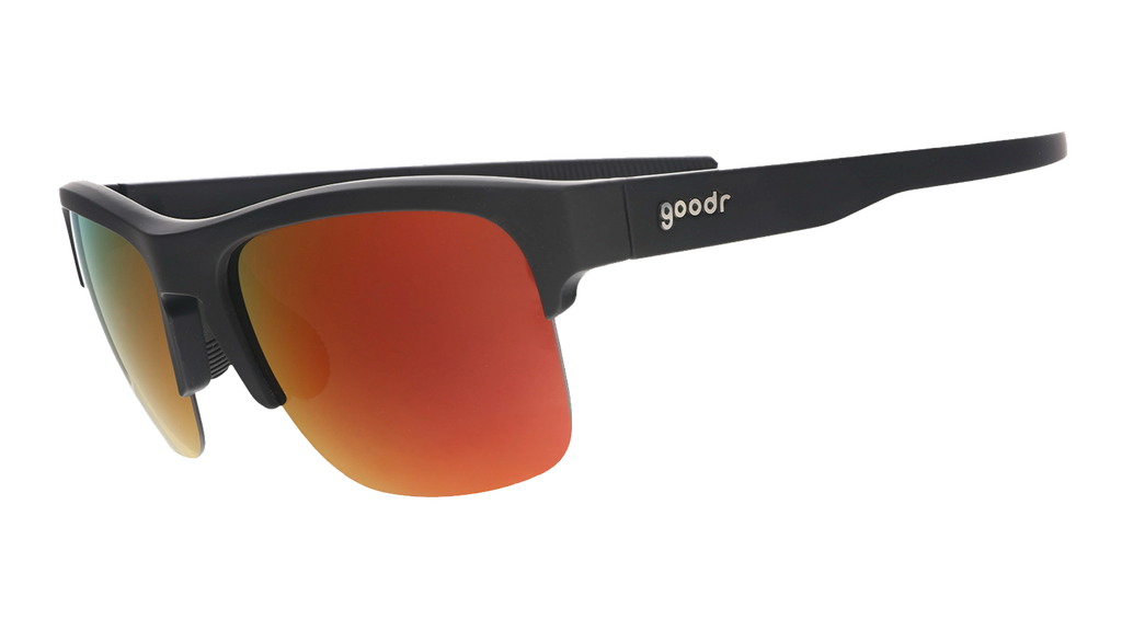 Three-quarter angle view of black sunnies with half-rim frames+orange reflective lenses on a white background.