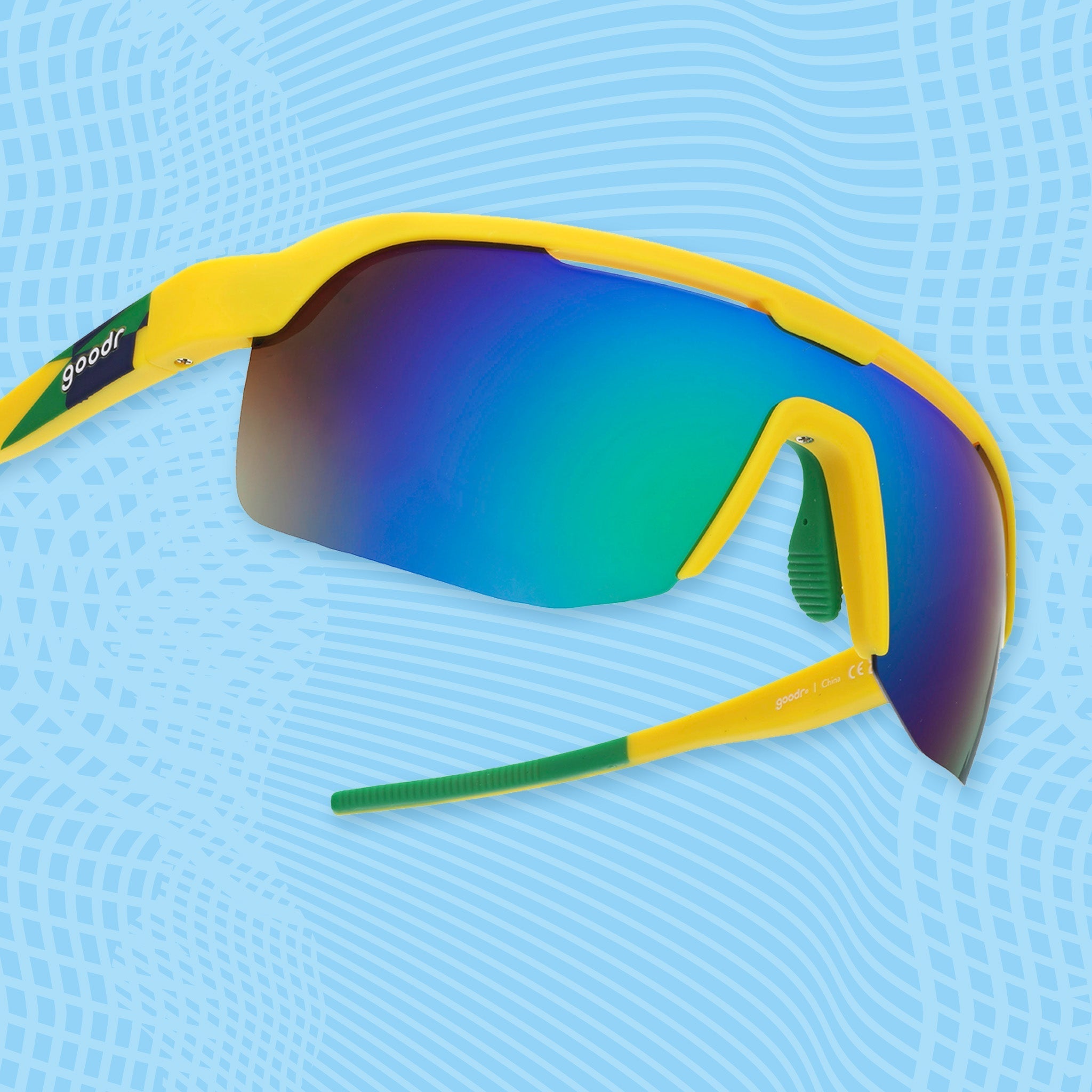 Yellow shield sunglasses with light green mirrored lenses on a blue patterned background.