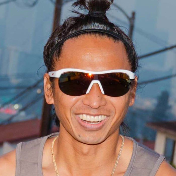 High-angle view of a model wearing white wrap shield sunglasses with red accents and fire-red reflective lenses.