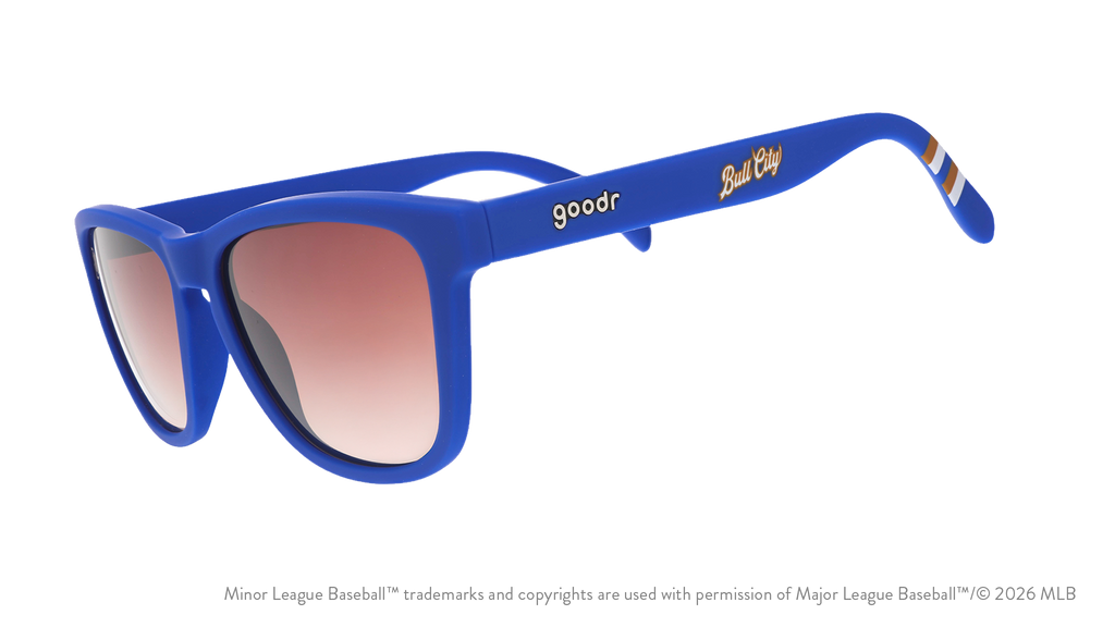 Three-quarter angle view of shades. Blue frames w/ stripe pattern+Bull City on temples. Brown gradient lenses.