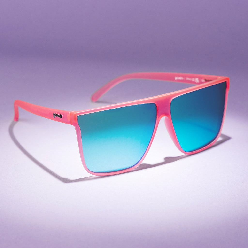 Three-quarter view of a pair of fashionable oversized pink flat-top glasses with blue reflective lenses.