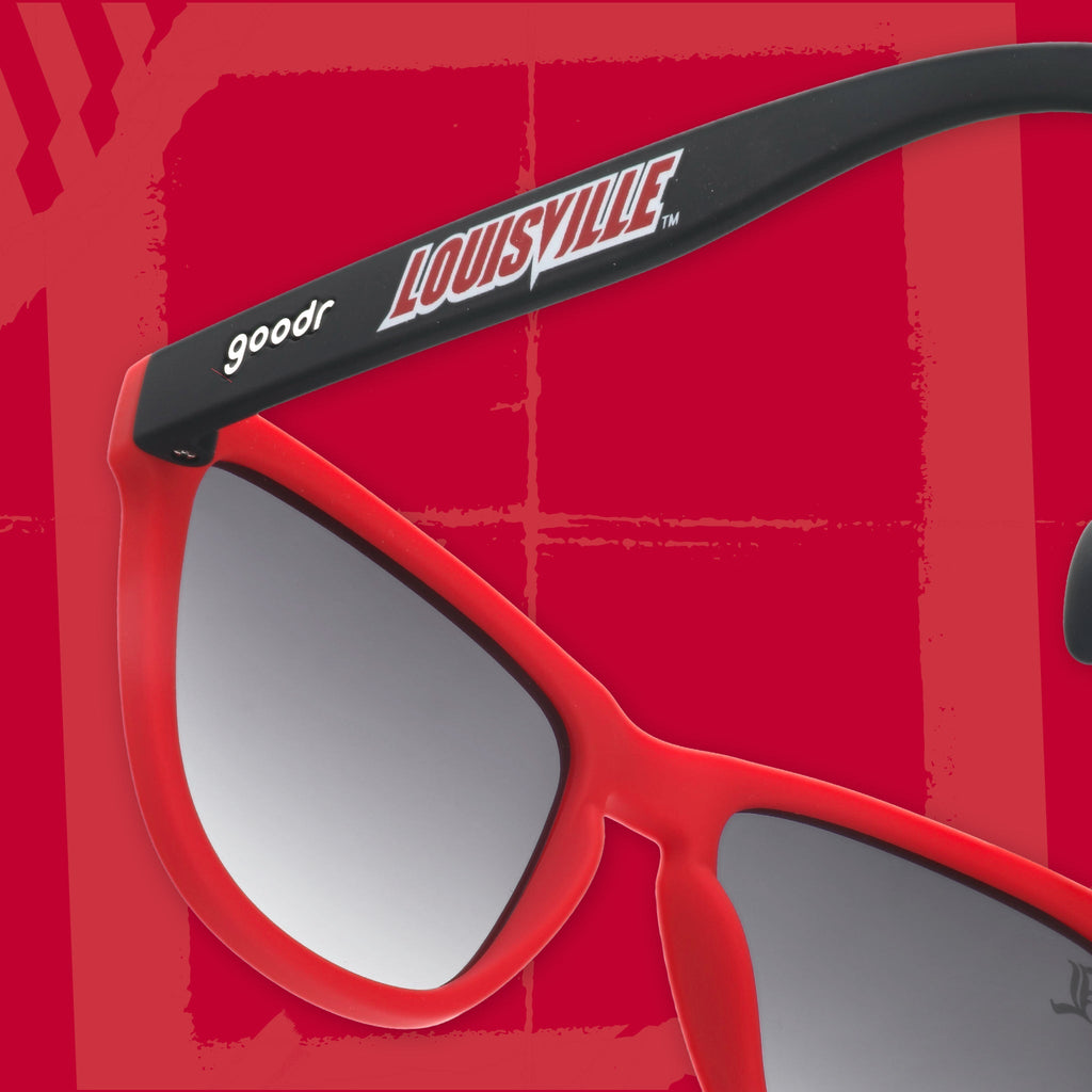Close-up back view of black and Cardinal red sunglasses featuring black gradient lenses and a Louisville logo on a red background.