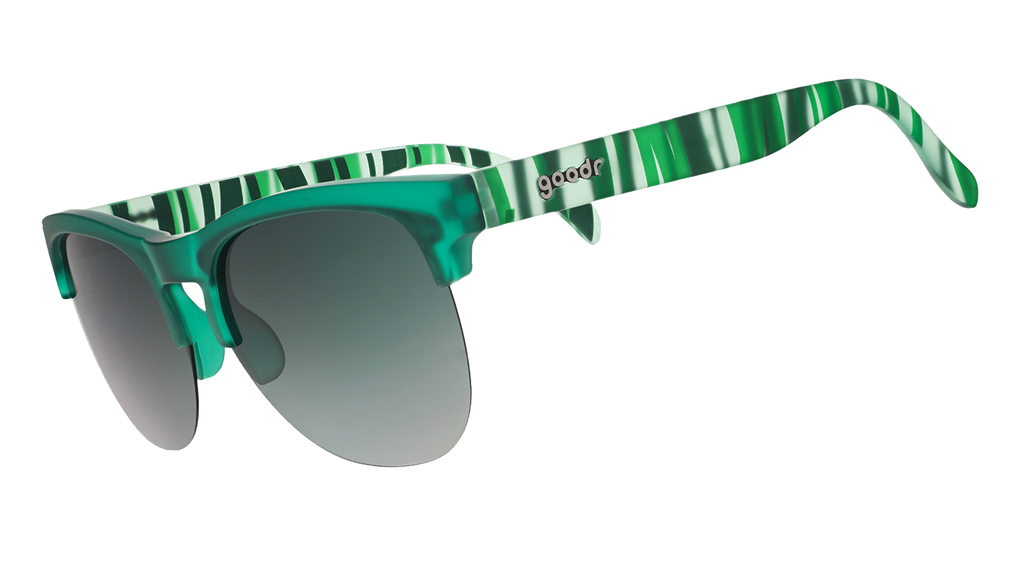 Green translucent sunglasses with mirrored lenses and striped temple arms on a blue patterned background.