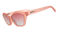 Three-quarter angle view of geometric sunglasses with translucent coral pink frames and gradient lenses against a white background.