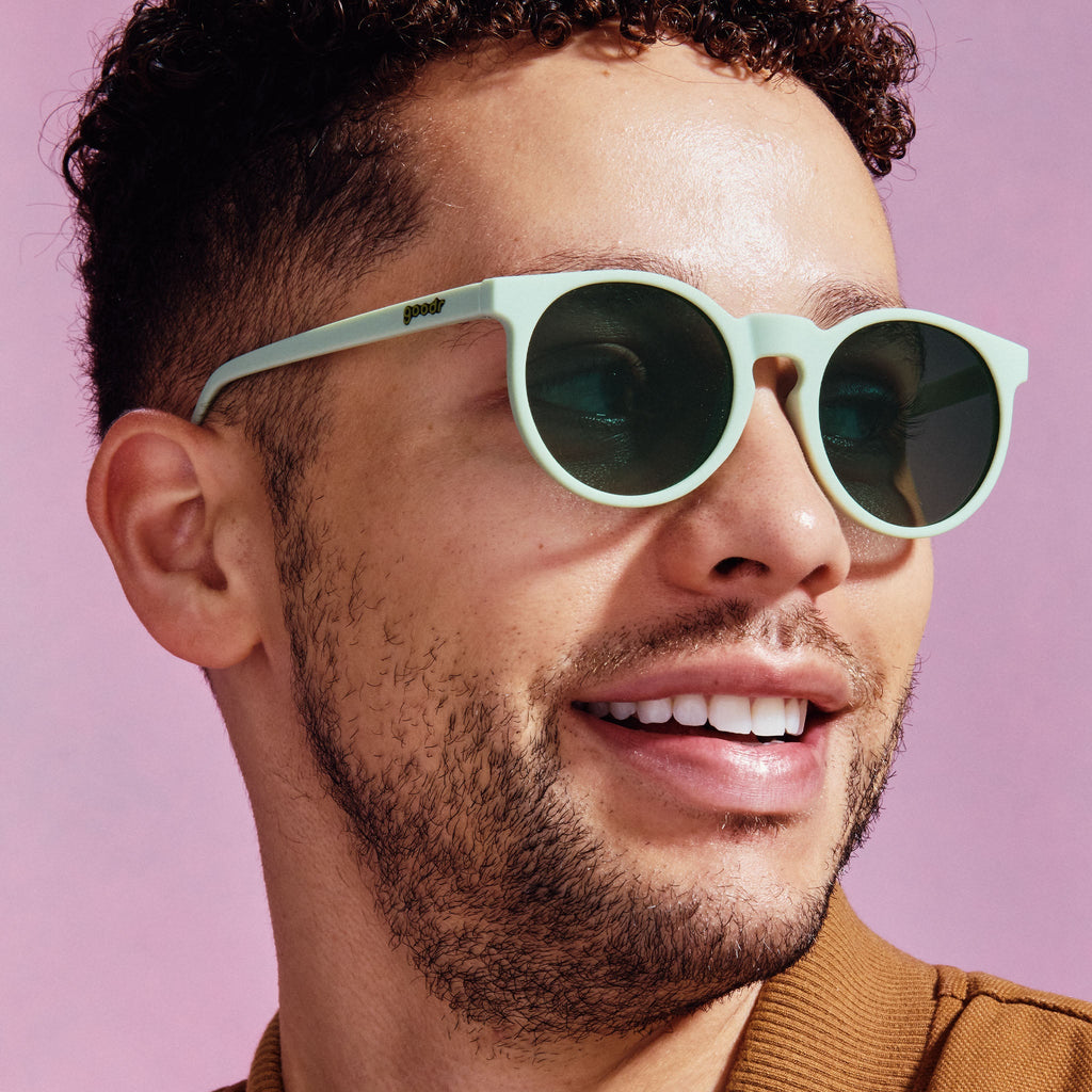A pair of round sunglasses with mint green frames.