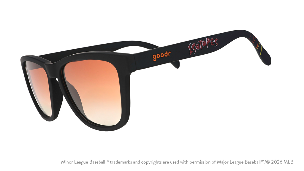 Three-quarter angle view of shades tilted down. Black frames w/ Isotopes + logo on temples. Amber reflective lenses.