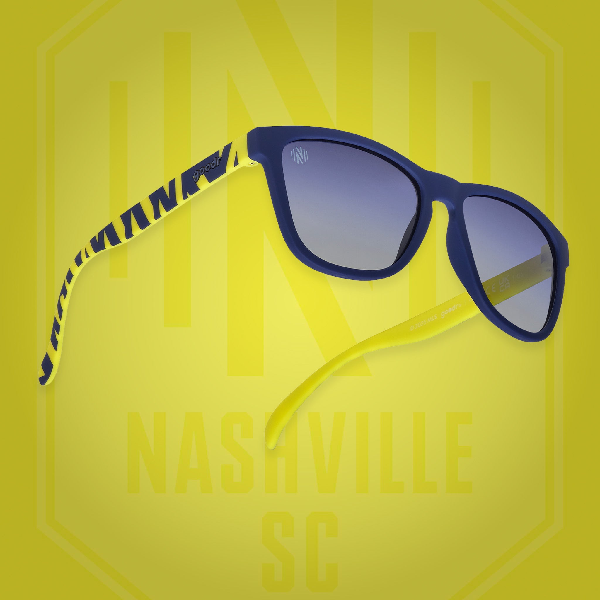 Angled view of shades tilted up. Blue frames w/striped yellow pattern+Nashville SC on temples. Blue gradient lenses.