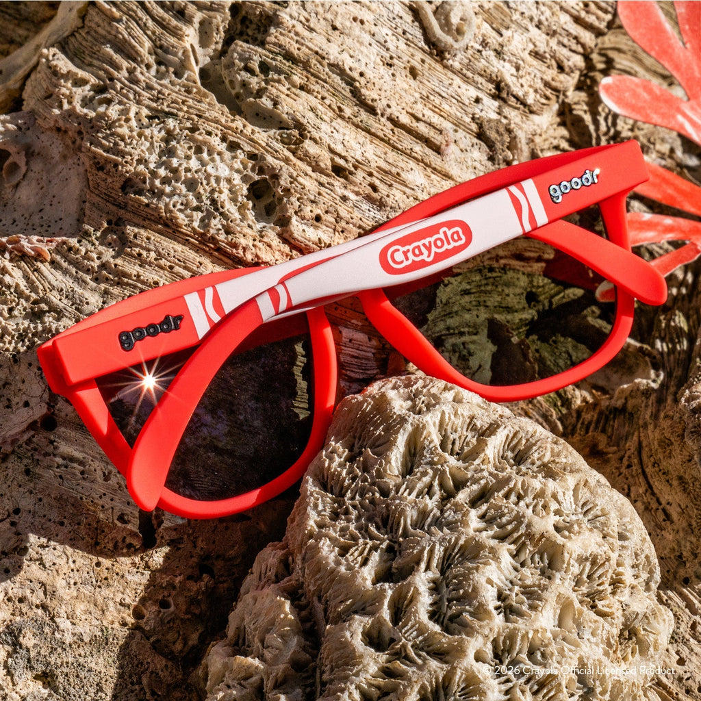 Back view of folded coral sunglasses w/ white Crayola marker pattern+burnt orange reflective lenses on a reef.