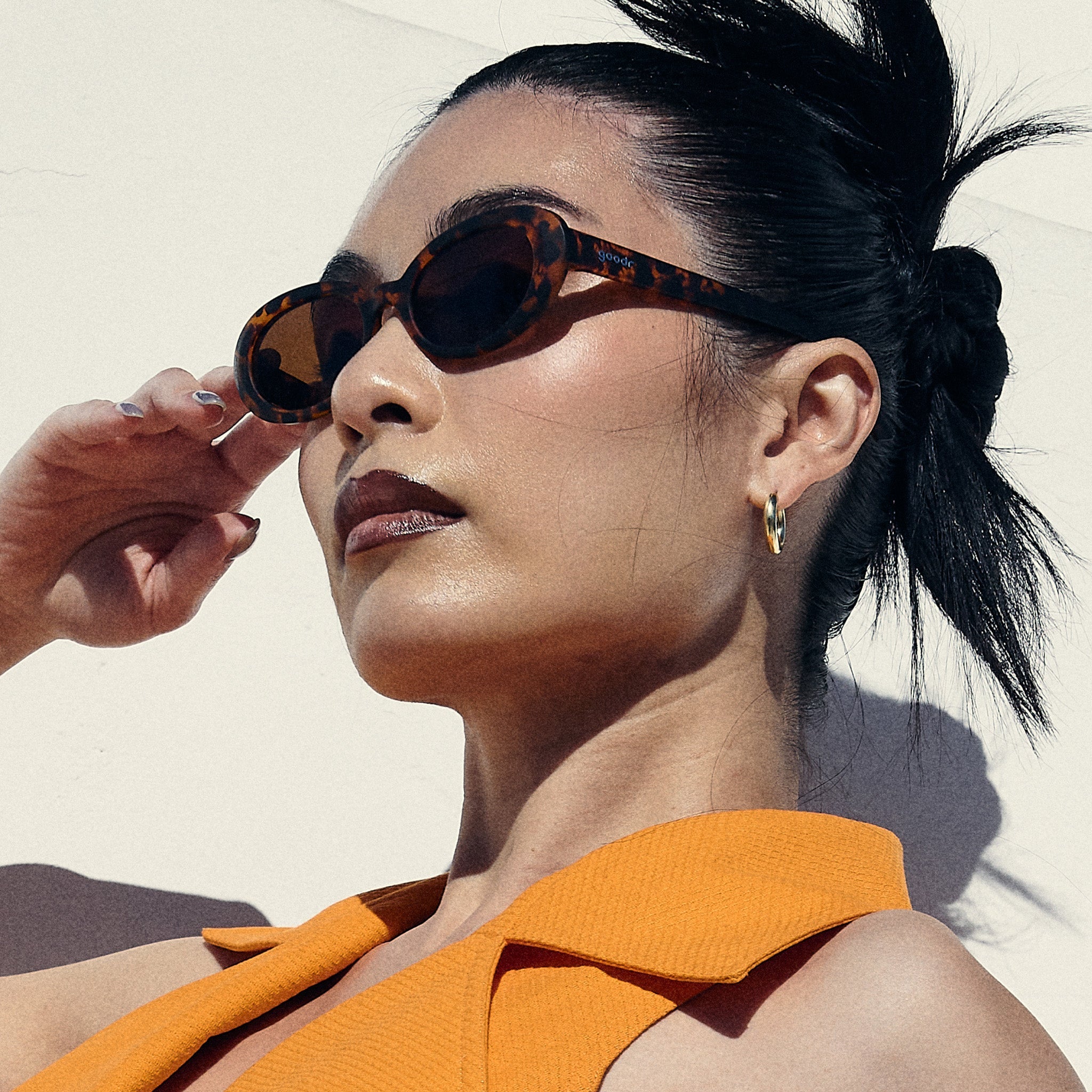 Side profile of a woman posing, wearing oval tortoiseshell sunglasses with brown polarized lenses.