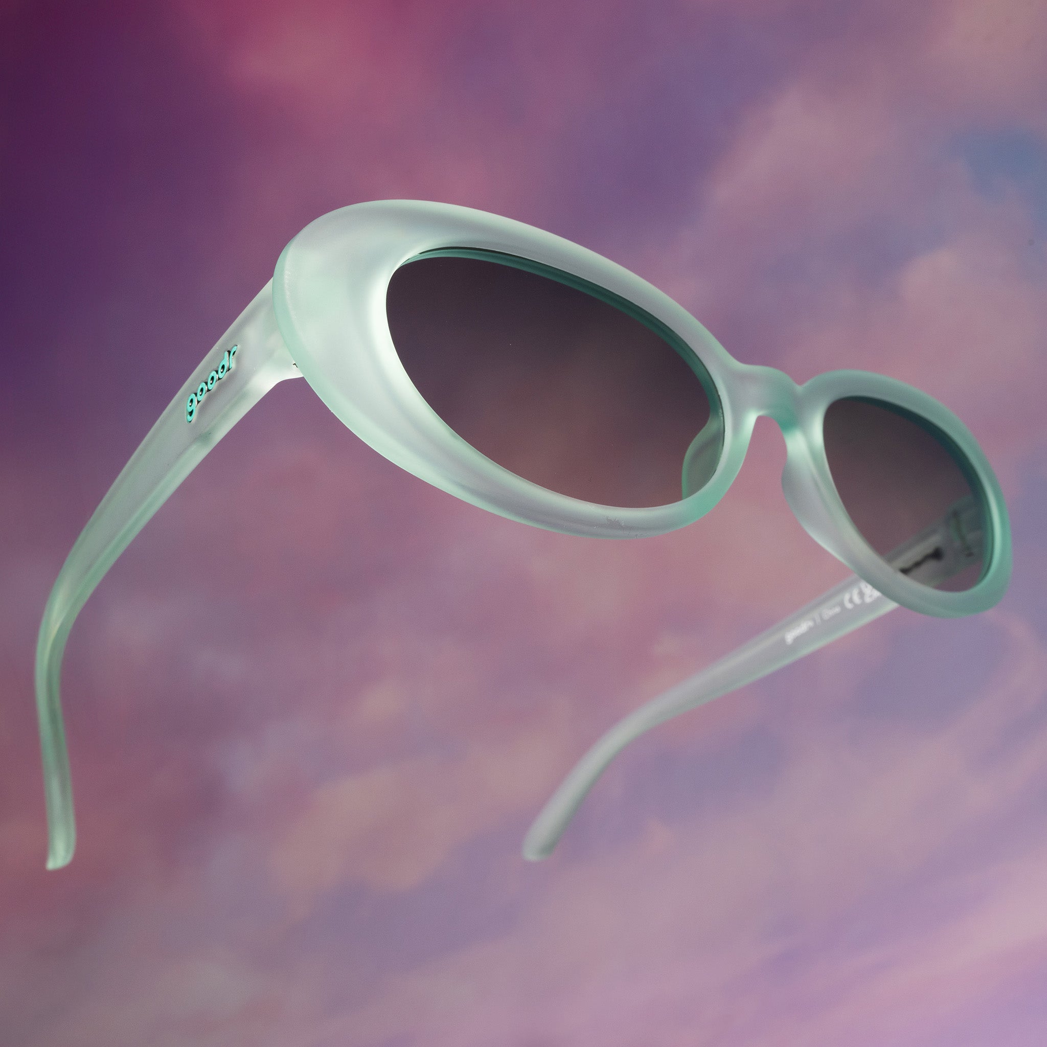 Three-quarter angle view of translucent pale green oval Beat G shades floating against a purplish-pink backdrop.
