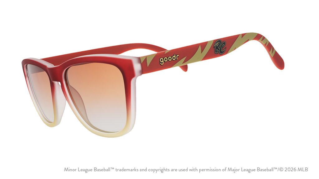 Three-quarter angle view of sunglasses tilted down. Brown + red frames w/ RC on temples + amber gradient lenses.