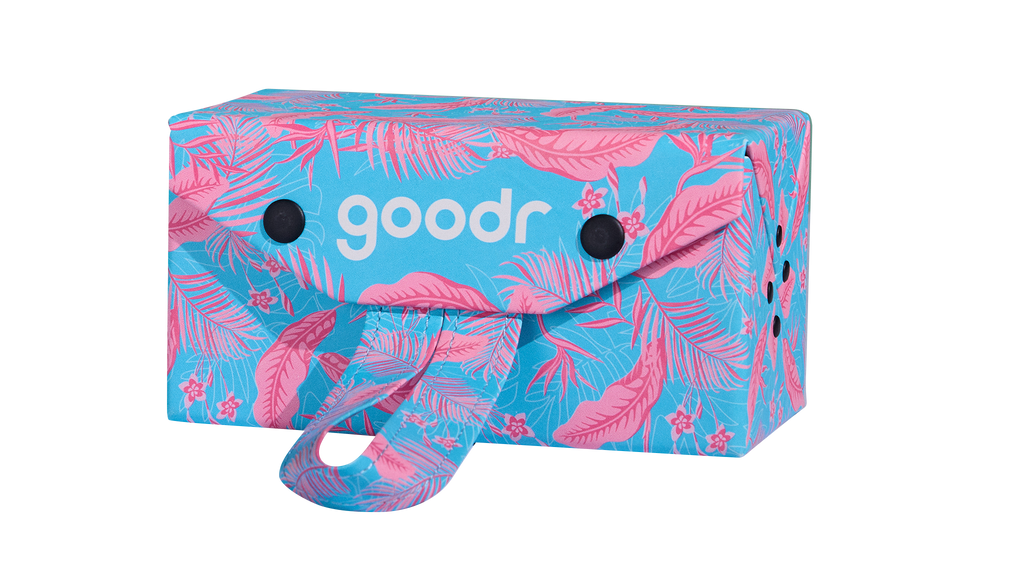 Three-quarter angle view of a rectangular hard cloth sunglasses case. The case features a tropical pink and blue design and has a carrying loop.