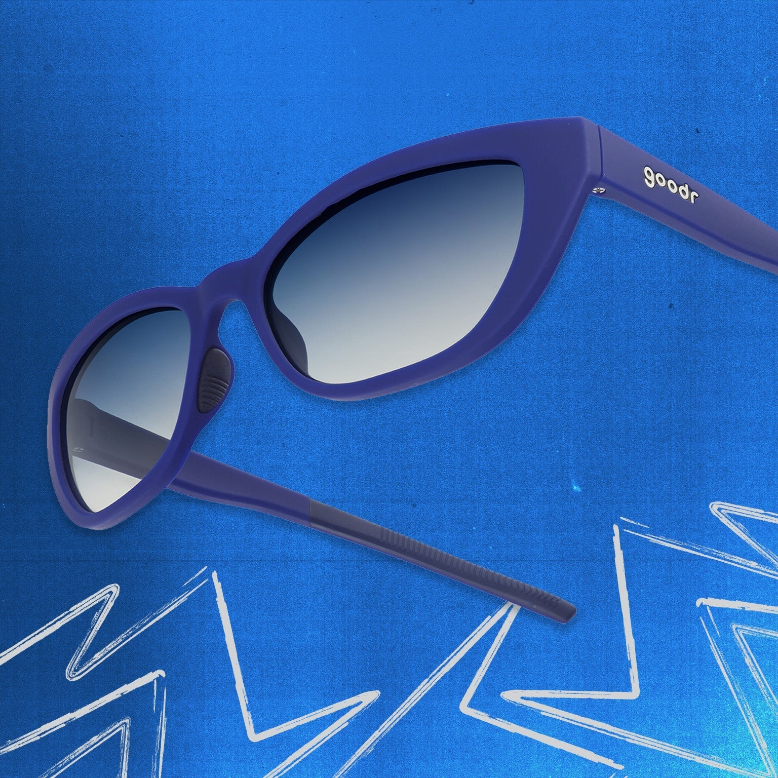 Three-quarter angle view of navy blue cat eye shades with blue gradient lenses tilted up on a blue background.