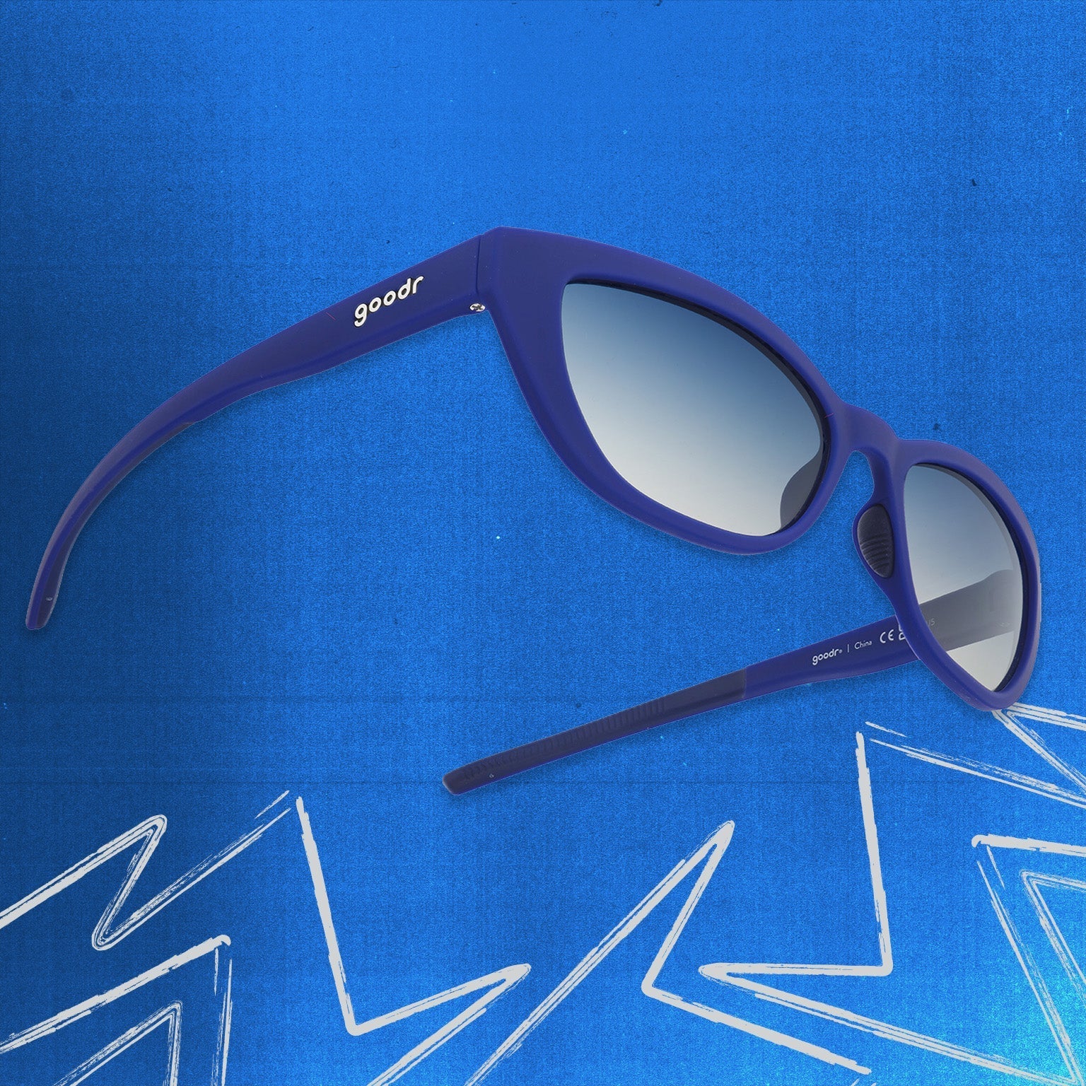 Three-quarter angle view of navy blue cat eye shades with blue gradient lenses tilted up on a blue background.