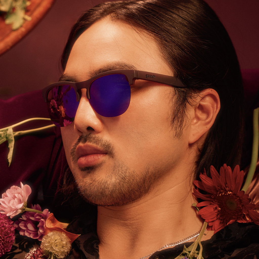 Side profile of a man wearing translucent purple half-rim sunglasses with purple reflective lenses.
