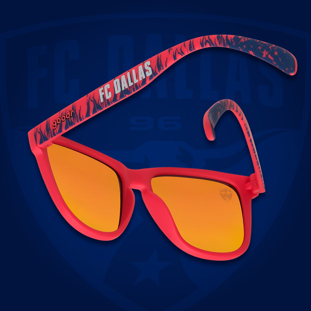 Back view of sunglasses tilted down. Red frames w/blue flames+FC Dallas on temples. Amber reflective lenses.