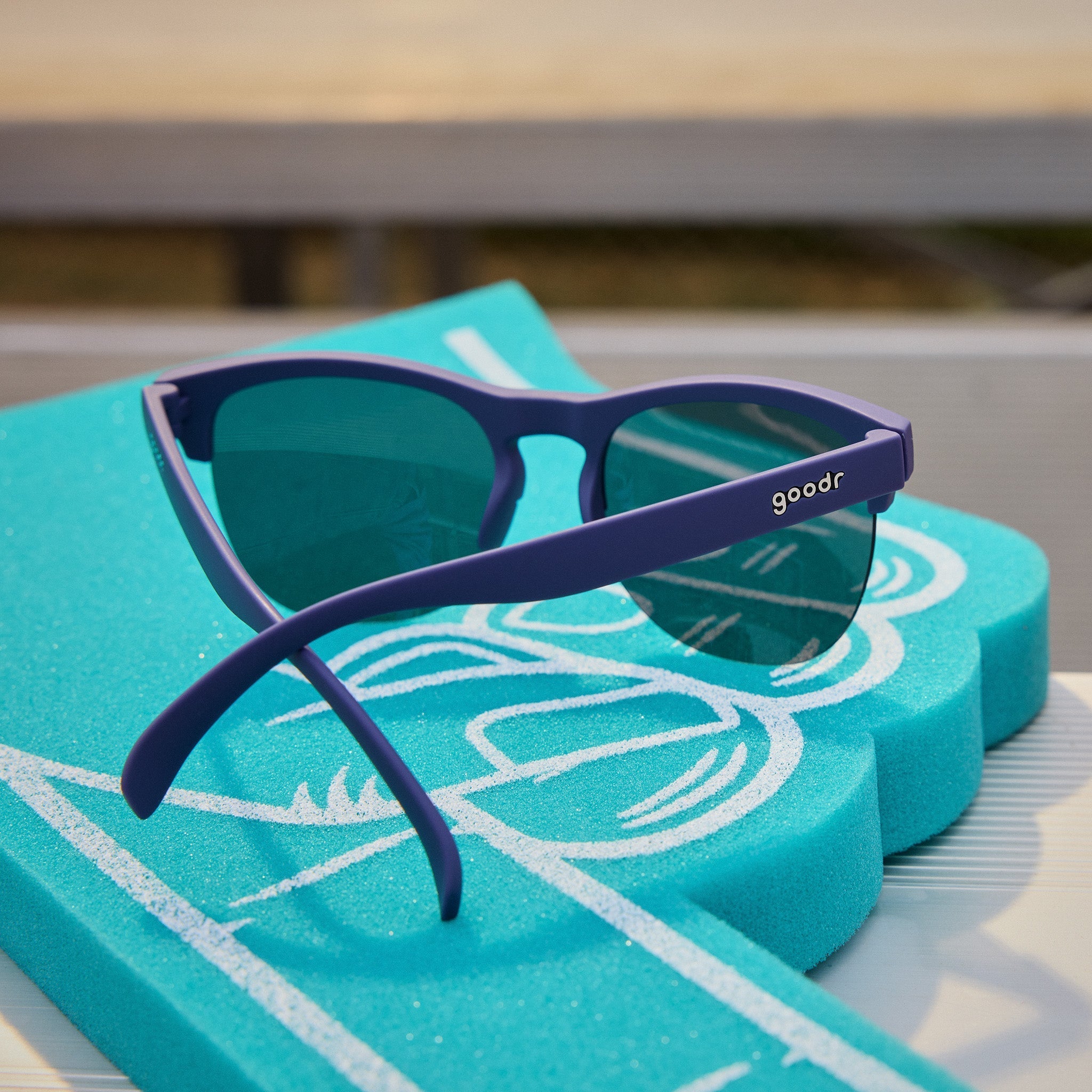 Back angle view of stylish navy blue half-rim sunglasses with chrome reflective lenses sitting atop bleachers.
