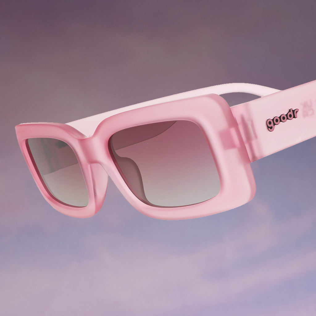 Temple shot of translucent pink Luxe G sunnies with purple gradient lenses floating against a purplish cloud-like backdrop.