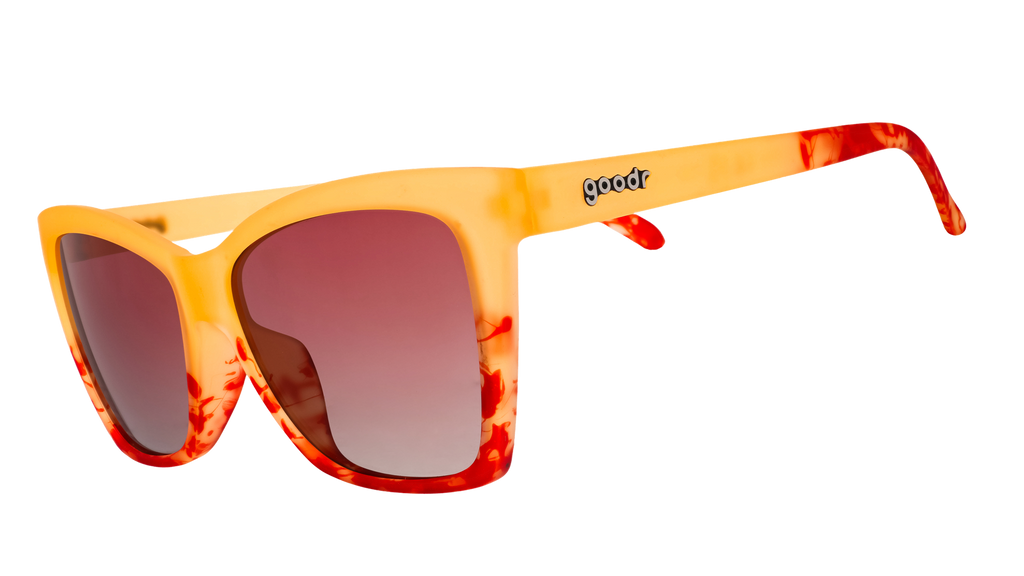 Three-quarter angle view of translucent yellow-orange sunglasses with red hand-painted whirls & rose ocean gradient lenses.