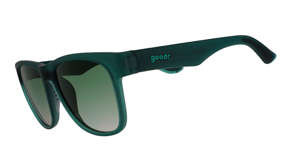 Three-quarter angle view of large dark teal sunglasses with green gradient lenses.