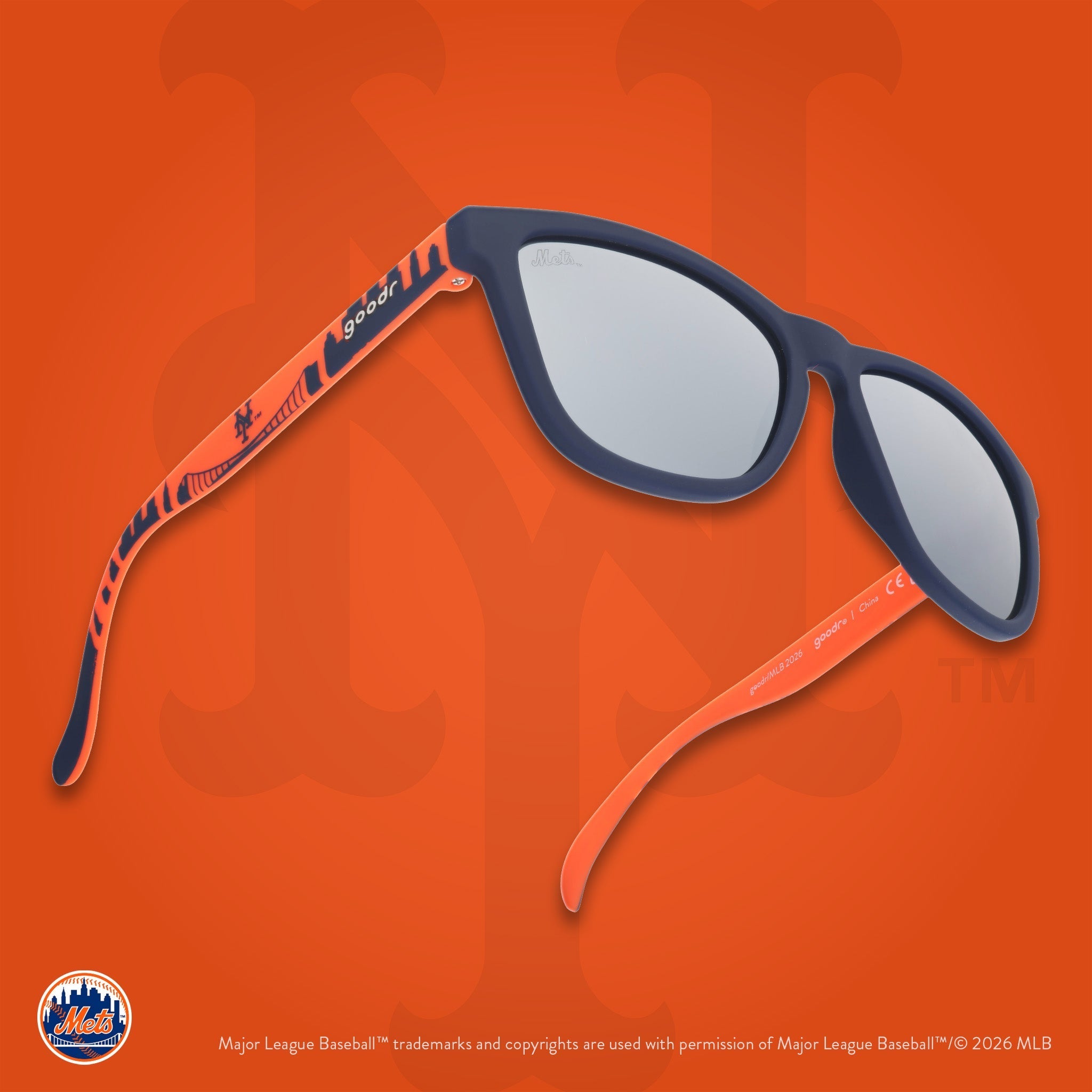 Three-quarter angle view of a pair of Mets sunnies floating against an orange background featuring the team's NY logo.