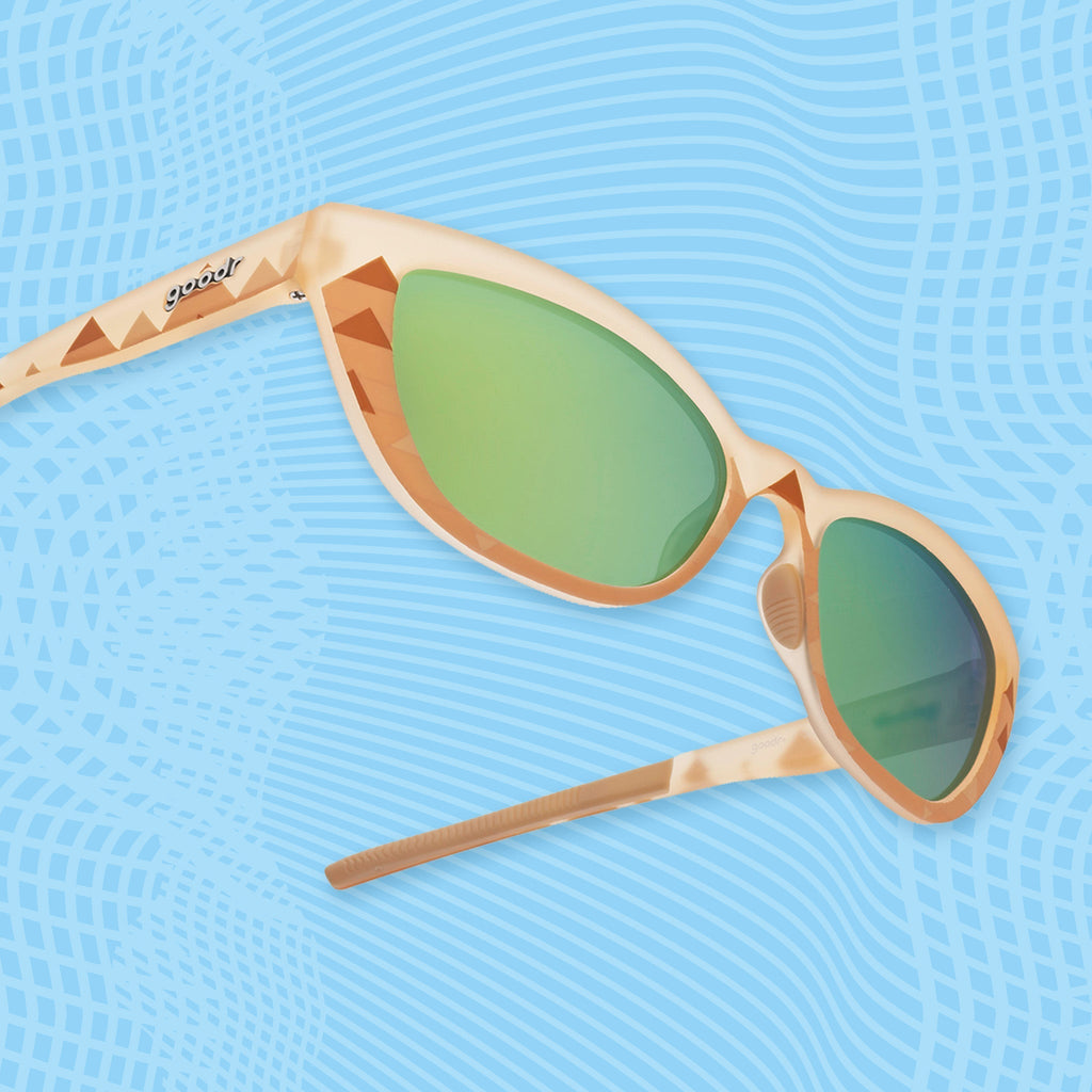 Light brown sunglasses with green mirrored lenses and pyramid-inspired geometric patterns on blue.