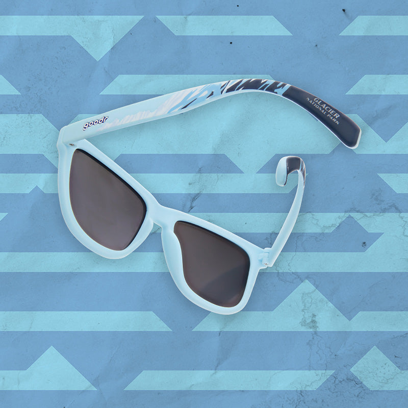 Blue sunglasses with "Glacier National Park" on the temple, with shades of blue and white to mimic a glacier design along the temples.