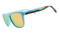 Pair of sunglasses with light blue frames and reflective yellow-orange lenses. The arms feature a vibrant tropical design with illustrations of waves and a sunset gradient.