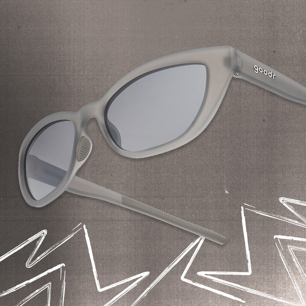 Three-quarter angle view of gray cat eye shades with chrome lenses tilted up on a gray background.