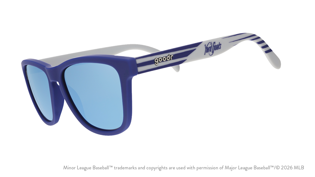 Three-quarter angle view of shades tilted down. Blue + gray frames w/ Yard Goats on temples. Teal reflective lenses.