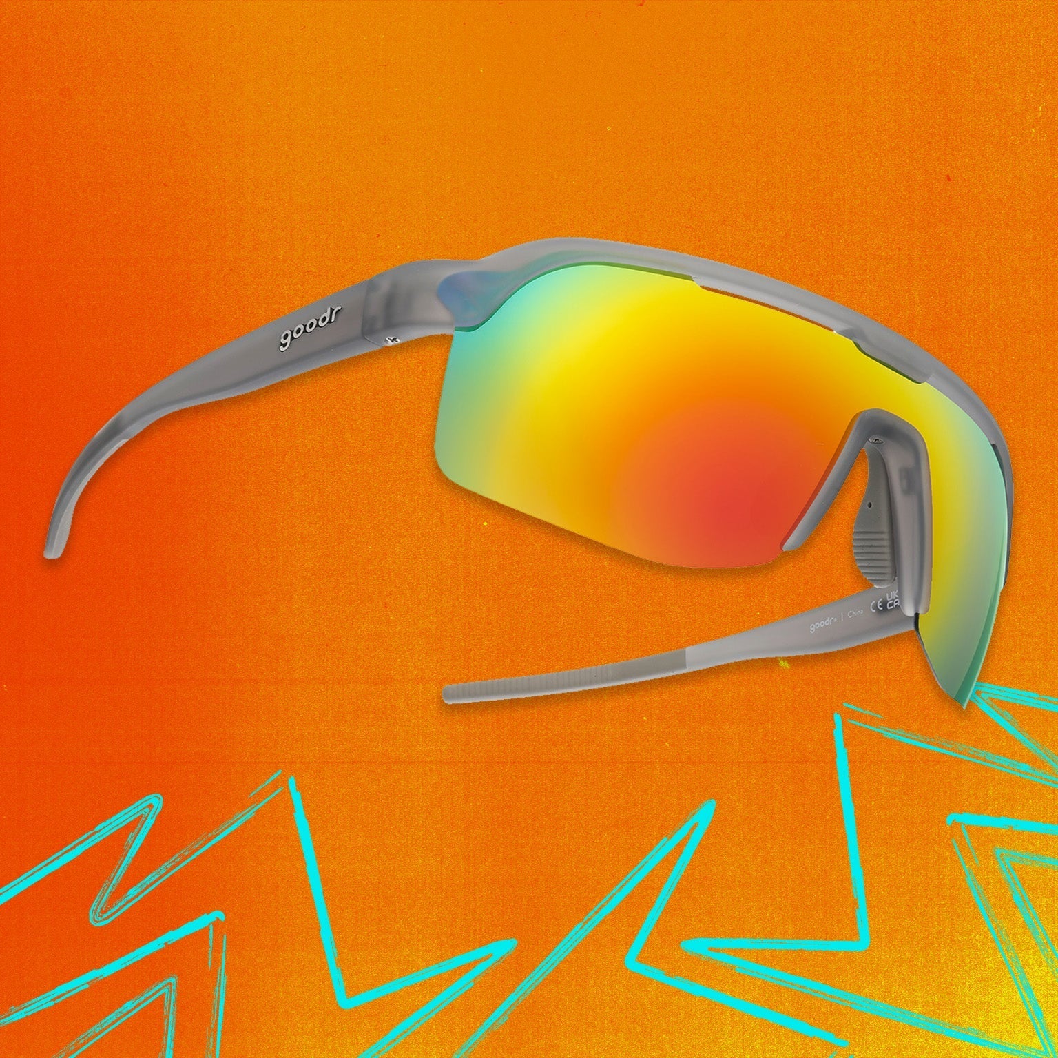 Three-quarter angle view of gray shield sunglasses with orange reflective wrap lenses tilted up on an orange background.