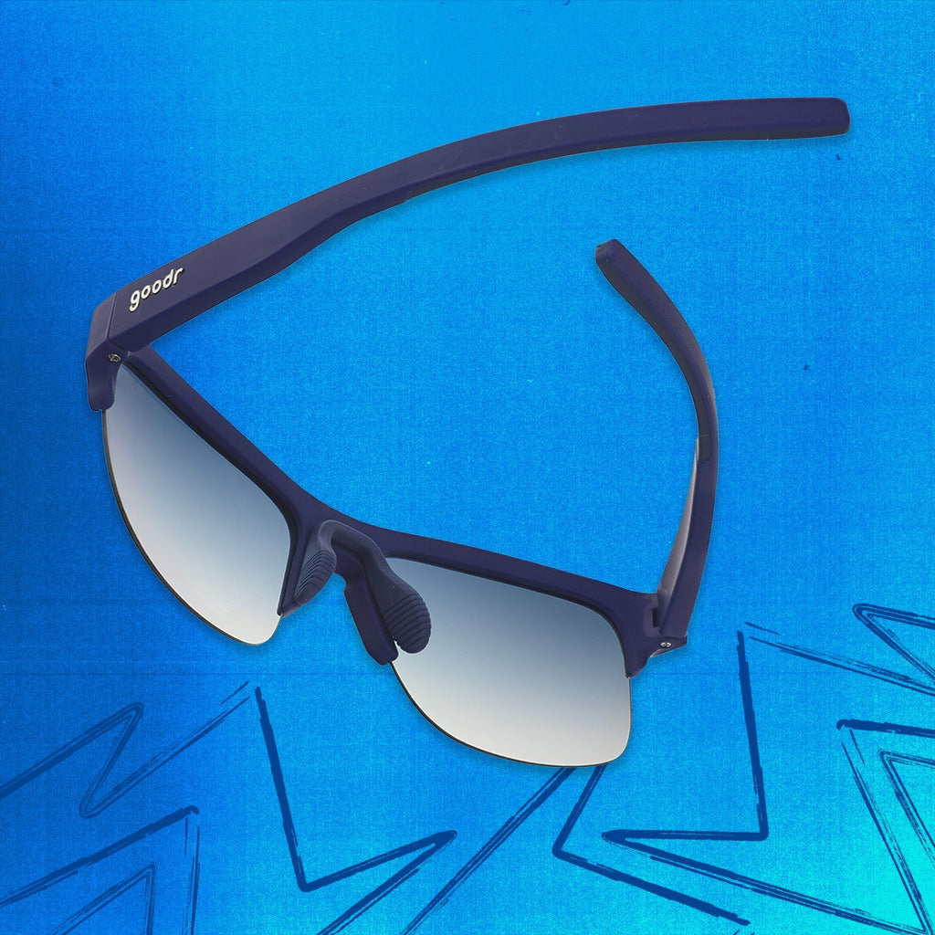 Three-quarter angle back view of navy blue shades with blue gradient lenses tilted down on a blue background.