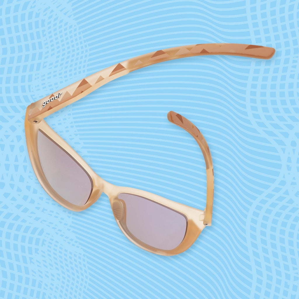 Angled view of light brown sunglasses with geometric temple patterns and mirrored green lenses.