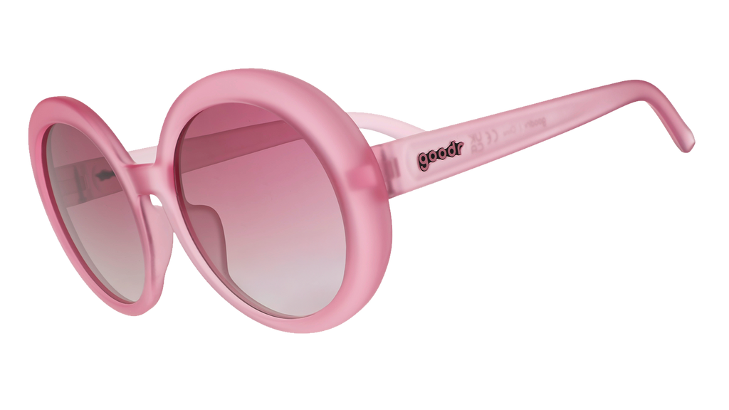 Three-quarter angle view of oversized, round, translucent pink Mood G sunglasses with purple gradient lenses.