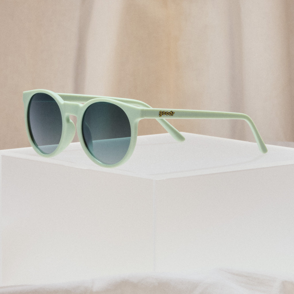 A pair of round sunglasses with mint green frames.