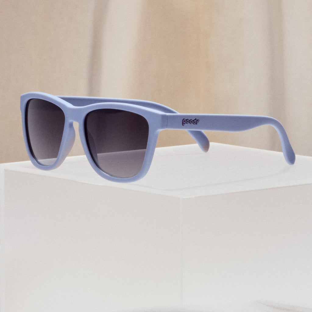 A pair of square sunglasses with lavender frames and lenses.