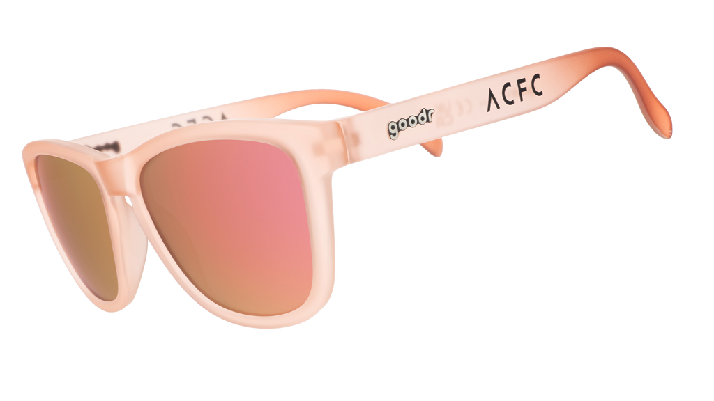 Three-quarter angle view of translucent pink sol rosa sunglasses with reflective champagne gold lenses & ACFC logo.