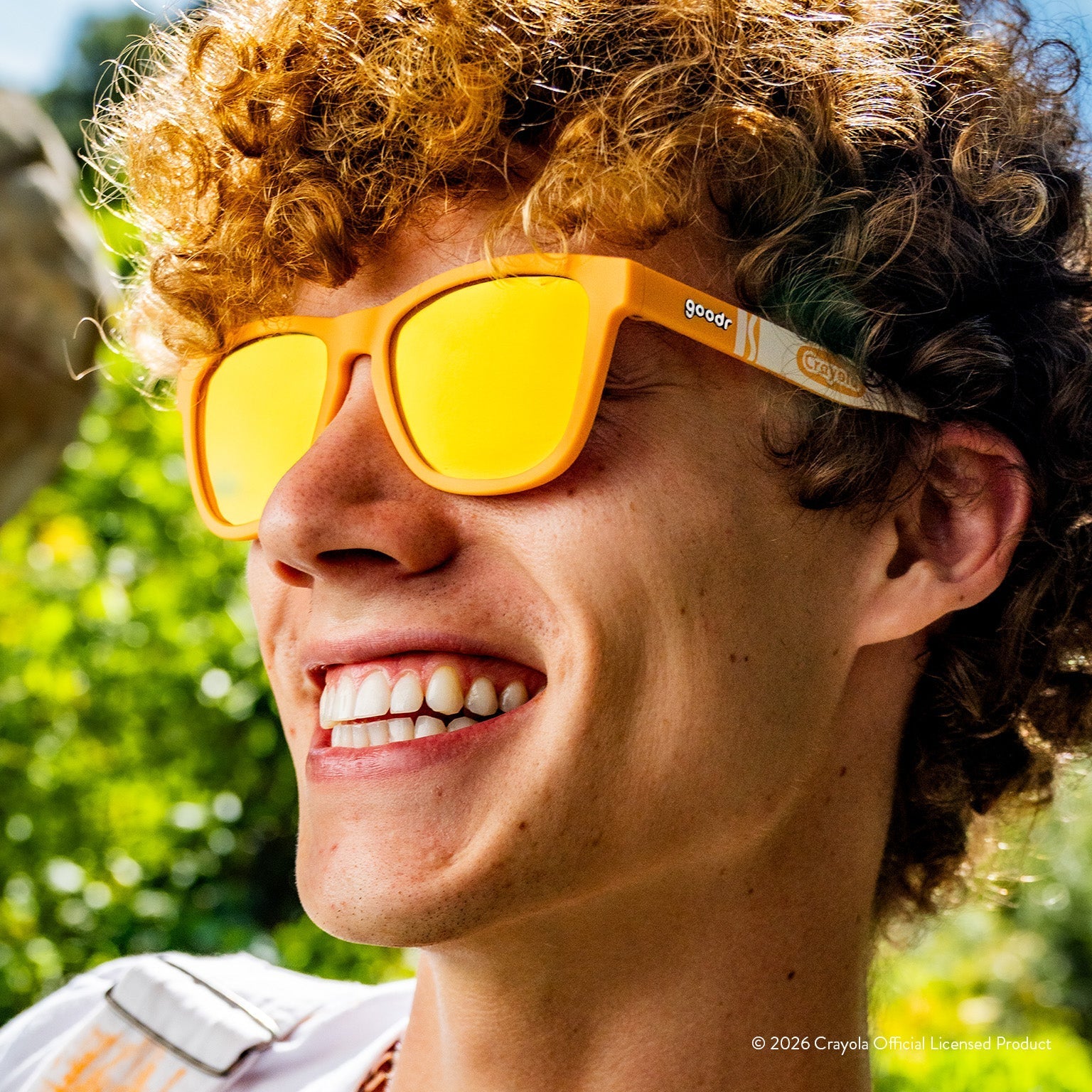 Man smiling while wearing tan sunglasses w/ white Crayola marker pattern+amber reflective lenses.