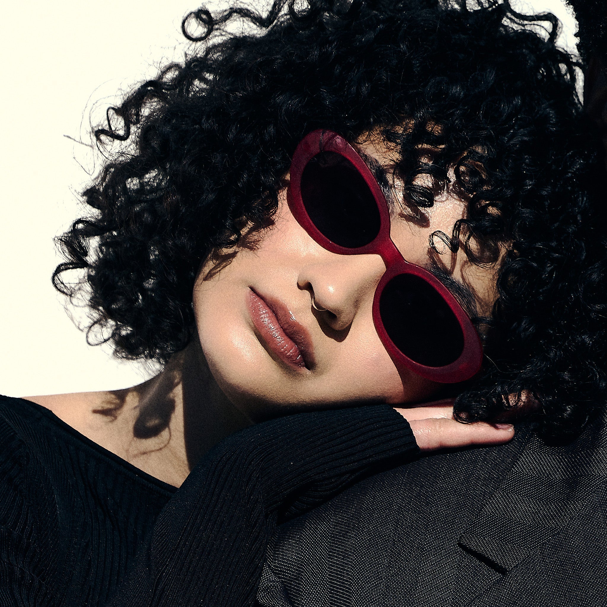 A woman poses while wearing hot pink oval sunglasses with dark red polarized lenses.
