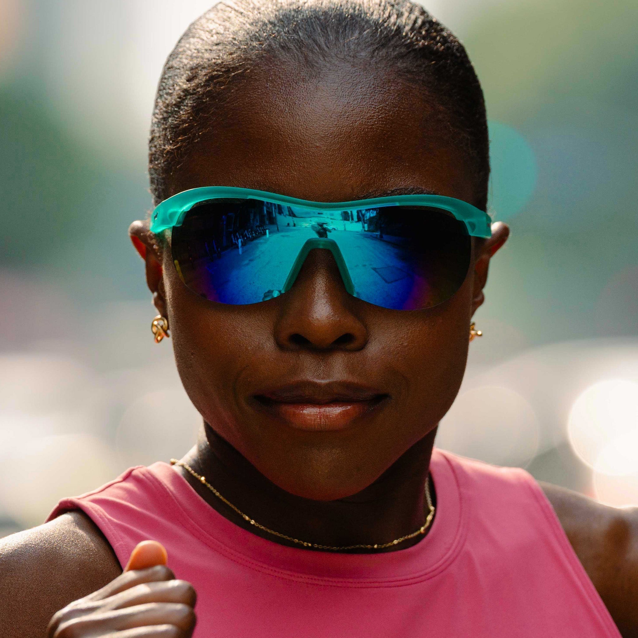 Model running while wearing translucent mint green wrap shield sunglasses with white-blue reflective lenses.