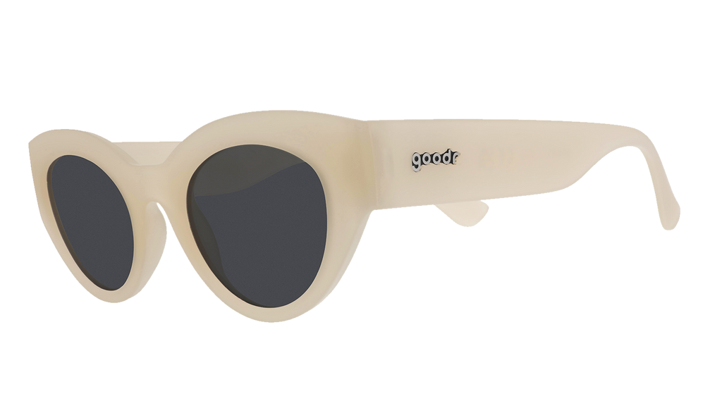 Three-quarter angle view of translucent soft cream, retro-inspired angled cat-eye sunglasses with black non-reflective lenses.