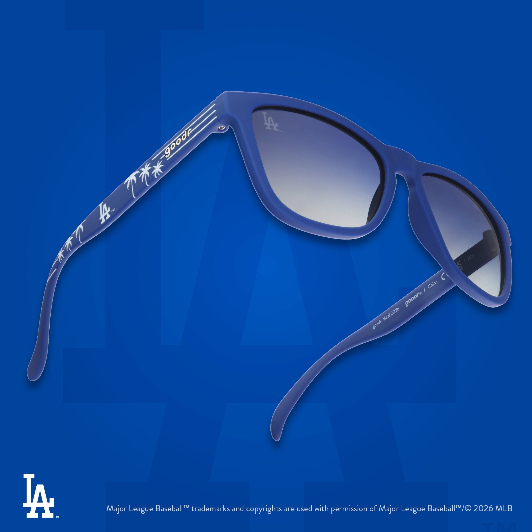 Three-quarter angle view of a pair of blue and white sunglasses featuring the Dodgers' LA logo and palm trees on the arm.