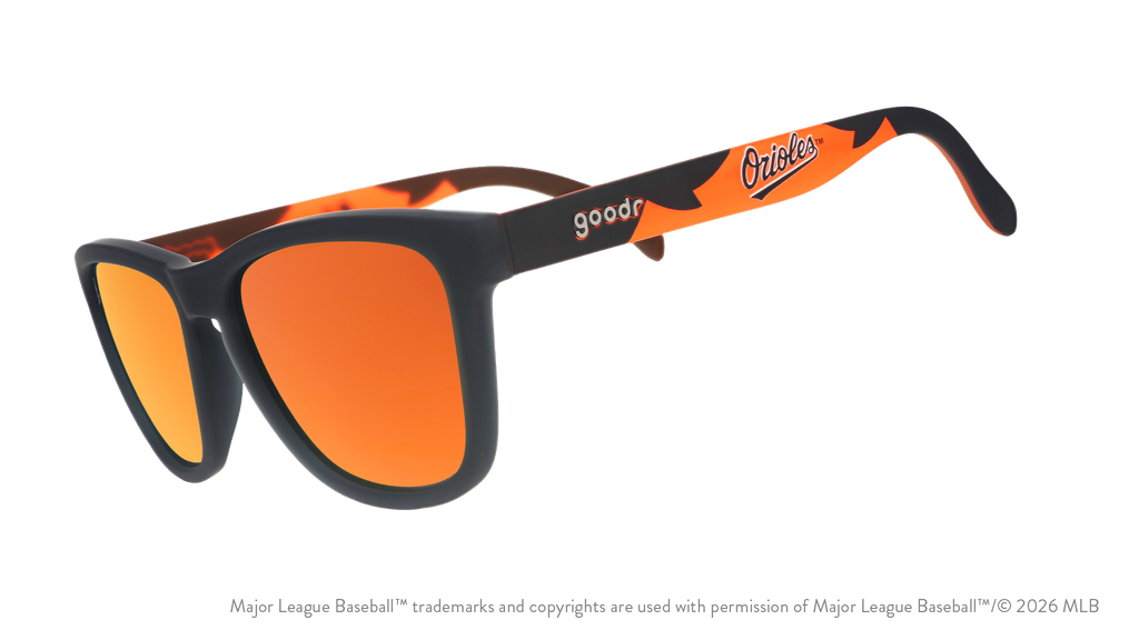Three-quarter angle view of a pair of black and orange sunglasses featuring the Orioles script logo on the arm.