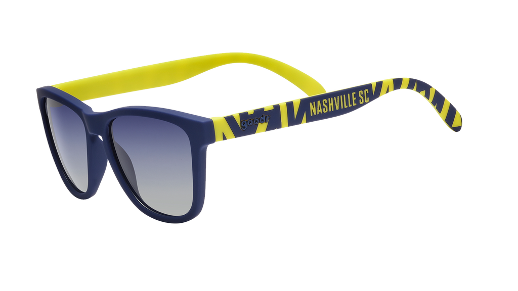 Angled view of shades tilted down. Blue frames w/striped yellow pattern+Nashville SC on temples. Blue gradient lenses.