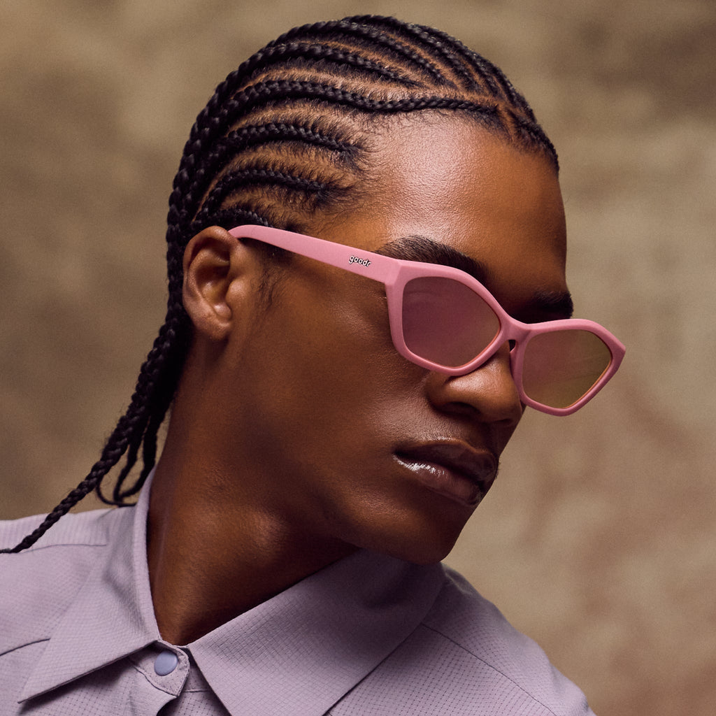 Person wearing pink sunglasses with a neutral background