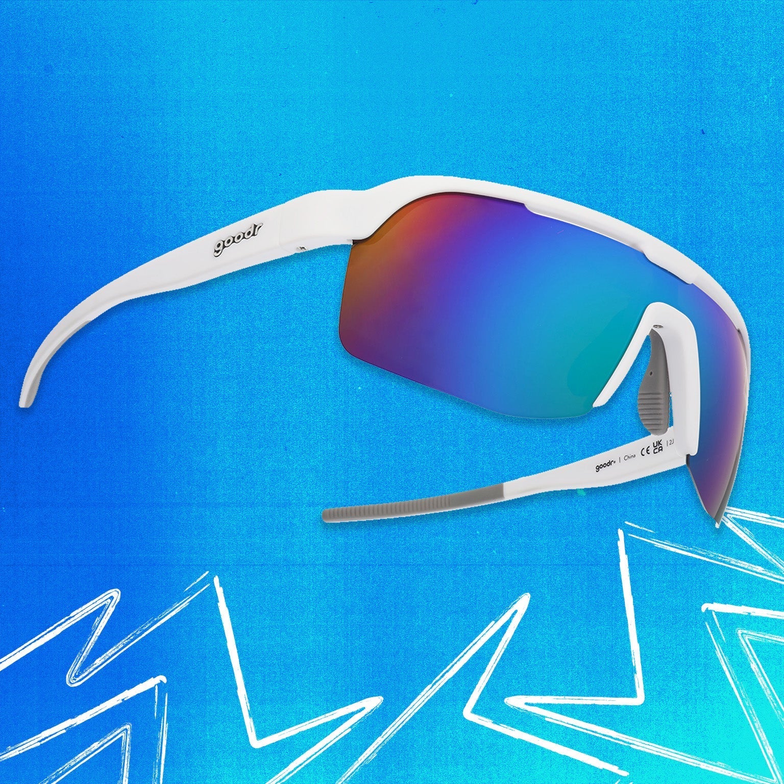 Three-quarter angle view of white shield sunglasses with green reflective wrap lenses tilted up on a blue background.